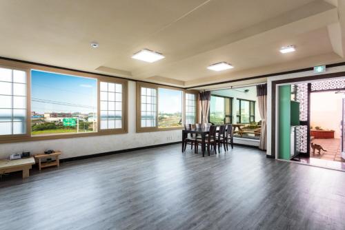 an empty room with tables and chairs and windows at Jeju Wayo Pension in Jeju