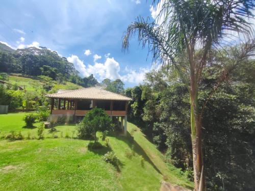 una casa en un campo con una palmera en Chalé da Lua - Parte Alta Parque Nacional de Itatiaia, en Itamonte