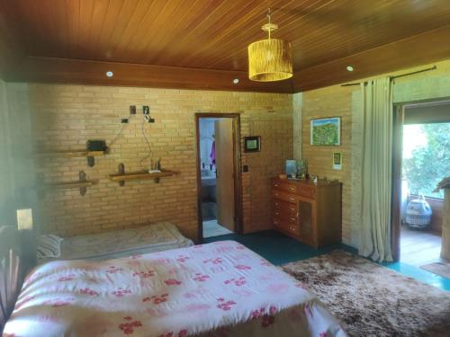 Un dormitorio con una cama y una pared de ladrillo. en Chalé da Lua - Parte Alta Parque Nacional de Itatiaia, en Itamonte