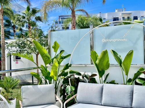 a patio with two white chairs and some plants at Aguacate Beach Apartamentos Playa Granada in Motril