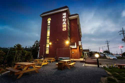 a group of picnic tables and benches in front of a building at Jeju Wayo Pension in Jeju