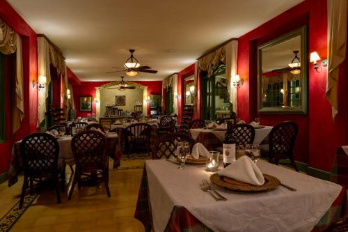 a restaurant with tables and chairs and red walls at Hotel Casa Turire in Turrialba