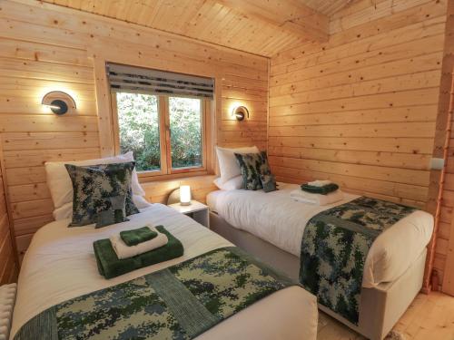 a bedroom with two beds in a log cabin at Little Lodge in Newton Stewart