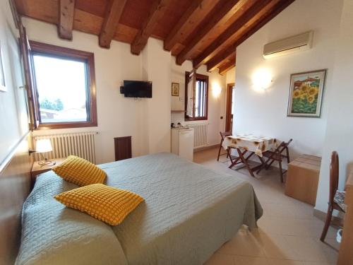 Un dormitorio con una cama con almohadas amarillas y una mesa. en Agriturismo Ca' Marcello, en Mira
