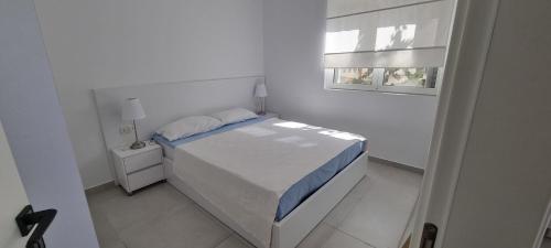 ein weißes Schlafzimmer mit einem Bett und einem Fenster in der Unterkunft Toni Apartment in Sarandë