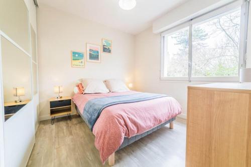 een slaapkamer met een bed met een roze deken en een raam bij #Le Concorde - Centre-ville - Terrasse - Parking in Brive-la-Gaillarde