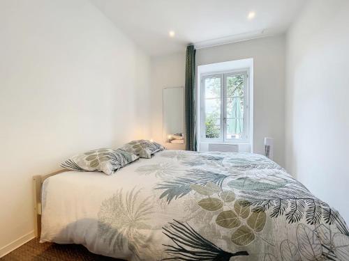 een slaapkamer met een bed met een dekbed en een raam bij L'Oustal Amans Rodat in Rodez