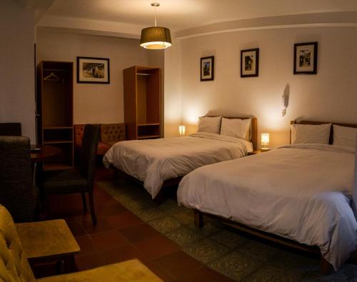 a hotel room with two beds and a chair at La Aurora in Huaraz