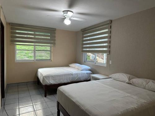 a bedroom with two beds and two windows at Casa Refugio Eterno in Etzatlán