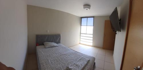 a small bedroom with a bed and a window at Apartamento duplex, con terraza y vista de Chiclayo in Chiclayo