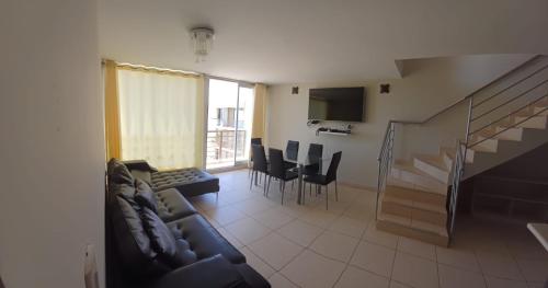 a living room with a couch and a table and chairs at Apartamento duplex, con terraza y vista de Chiclayo in Chiclayo