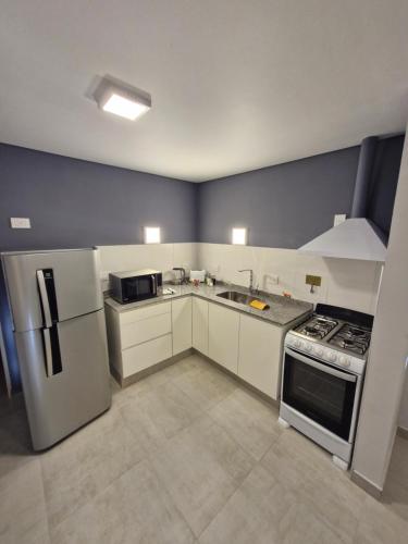 een keuken met witte kasten, een fornuis en een koelkast bij Austral Lofts in Puerto Madryn