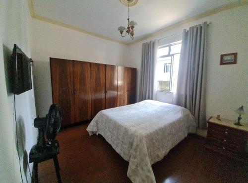 a bedroom with a bed with a wooden headboard and a window at Apartamento no Centro Parq Halfeld Juiz fora in Juiz de Fora