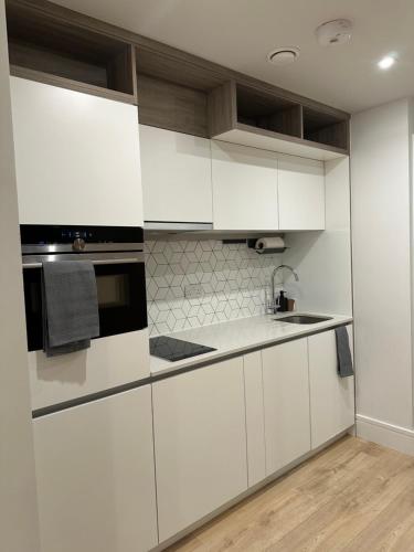 ロンドンにあるLuxury Capella Courtの白いキャビネットと黒い電子レンジ付きのキッチンが備わります。