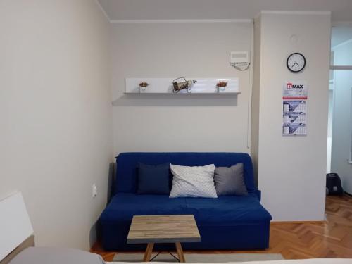 Sofá azul en la sala de estar con mesa en Apartman A-1, en Zajecar