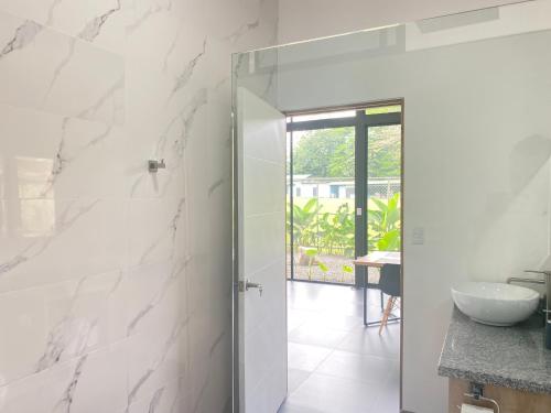 a bathroom with white marble walls and a glass door at Toucan home in Fortuna