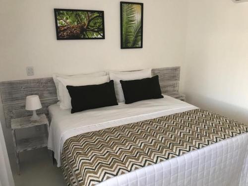 um quarto com uma grande cama branca e 2 almofadas em GIRASSÓIS - Suítes em Pipa