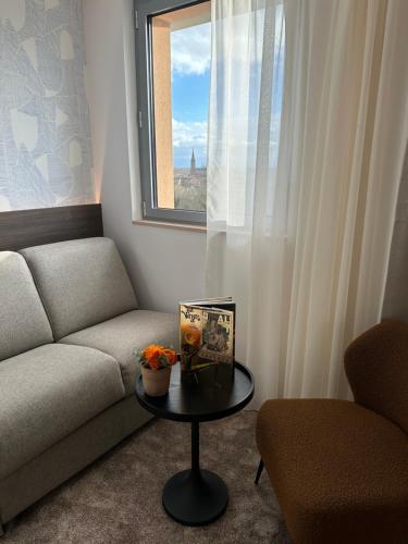 a living room with a couch and a table with a window at Dali Hôtel Montauban in Montauban