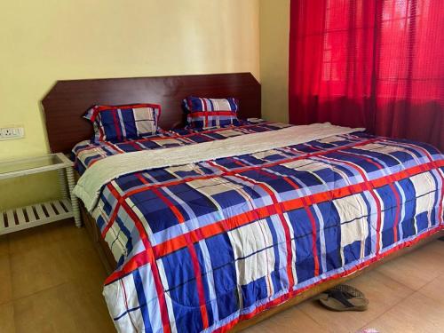 a bed with a blue and red blanket and pillows at Misty Dews (Bharat Builders) in Kodaikānāl