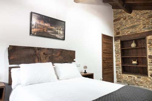 una camera con un letto bianco e un muro in pietra di Casa Rural Lar de Sanxes a Lugo
