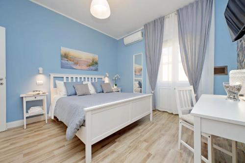 a blue bedroom with a white bed and a desk at PR APARTMENT - FIUMICINO ROME AIRPORT 9 Min - in Fiumicino