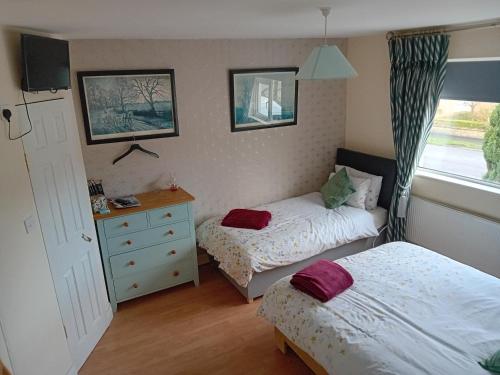 a bedroom with two beds and a dresser and a window at Cuan na bPiobairí in Mullingar