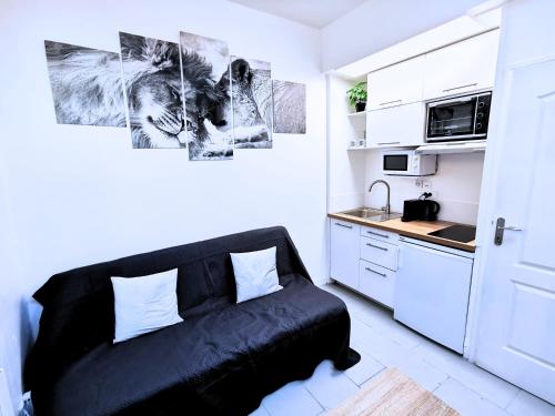 un salon avec un canapé noir dans une cuisine dans l'établissement Bagneux Paris RER B Confort Netflix, à Cachan