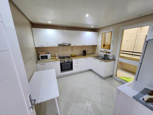 a kitchen with white cabinets and a white tile floor at Gouletteparadis in La Goulette
