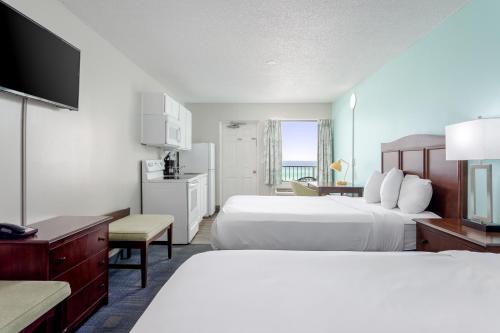 パナマ・シティ・ビーチにあるBikini Beach Resortのベッド2台とテレビが備わるホテルルームです。