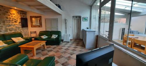ein Wohnzimmer mit grünen Möbeln und einem TV in der Unterkunft La Jubilotte in Beaumes-de-Venise
