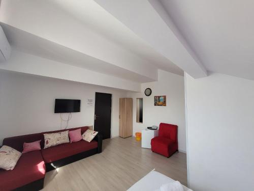 uma sala de estar com um sofá e uma cadeira vermelha em Casa Octaral em Eforie Nord