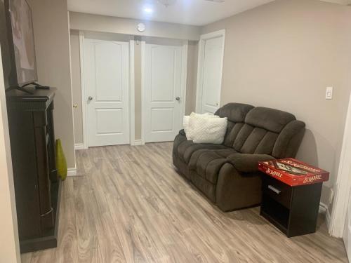 a living room with a brown couch and a television at 2 bedroom basement with private side entrance in Guelph