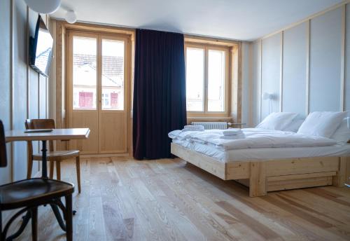 een slaapkamer met een groot bed, een tafel en een raam bij Hôtel-Restaurant du Cerf in Les Ponts-de-Martel