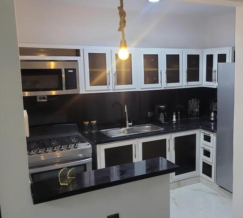 a kitchen with black counter tops and white cabinets at Rijos tower 3 in Santo Domingo