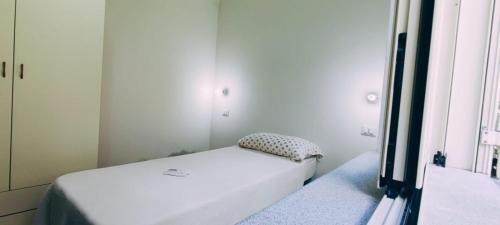 ein kleines weißes Bett in einem Zimmer mit Fenster in der Unterkunft Oasi love & relax in Maratea