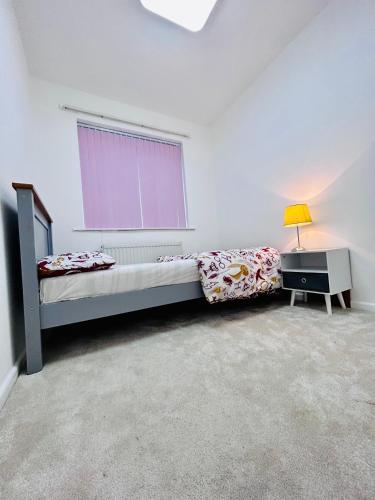 1 dormitorio con cama, ventana y lámpara en Room in Oldham, Manchester en Oldham