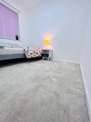 Habitación blanca con cama y lámpara. en Room in Oldham, Manchester en Oldham