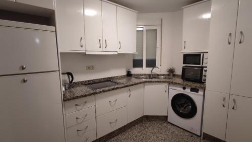 a kitchen with white cabinets and a washer and dryer at Apartamento VILLASOLETE in Fuengirola
