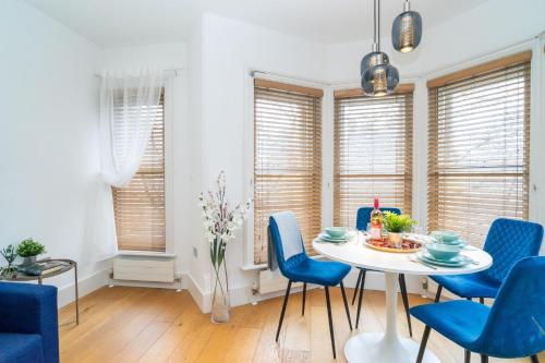 a dining room with a white table and blue chairs at Heart of London's West End / Pro Host in London