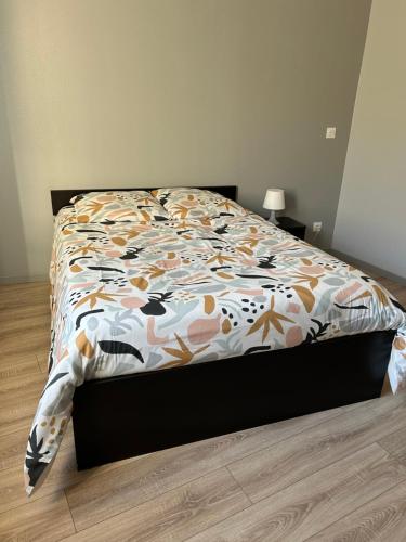 un lit avec une couette dessus dans une chambre dans l'établissement Charmant appartement en rez-de chaussée, à Saint-Marcel