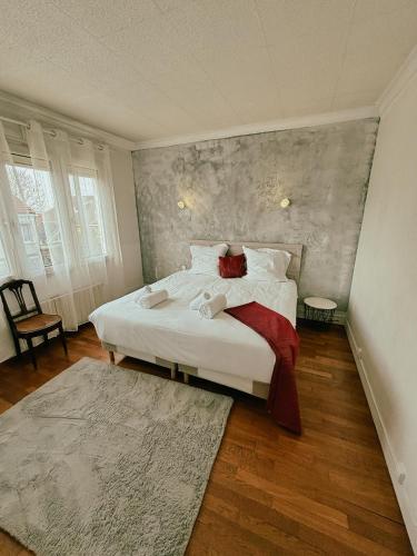 um quarto com uma cama com lençóis brancos e almofadas vermelhas em Duplex avec jardin - Proche Paris - Disneyland - RER - em Noisy-le-Grand