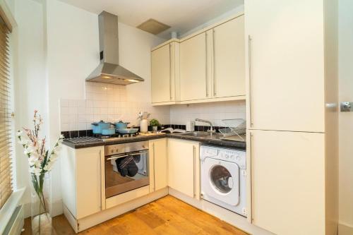 a kitchen with white cabinets and a washer and dryer at Heart of London's West End / Pro Host in London