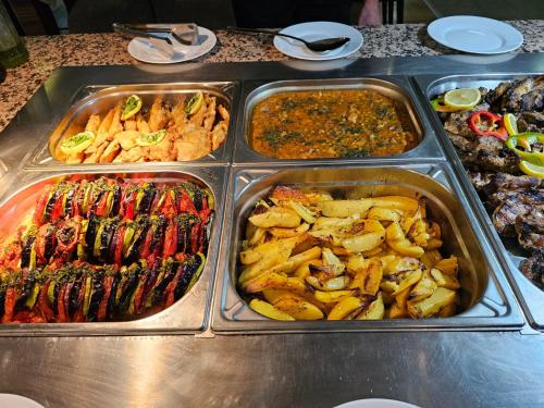 a buffet line with trays of different types of food at Gardenia Park Hotel in Bansko
