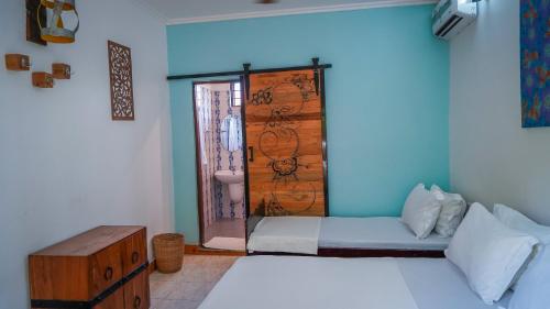 ナングウィにあるNungwi Houseのベッド1台とバスルームへのドアが備わる客室です。