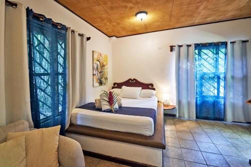 a bedroom with a bed and a couch and windows at Casas Mal Pais in Mal País