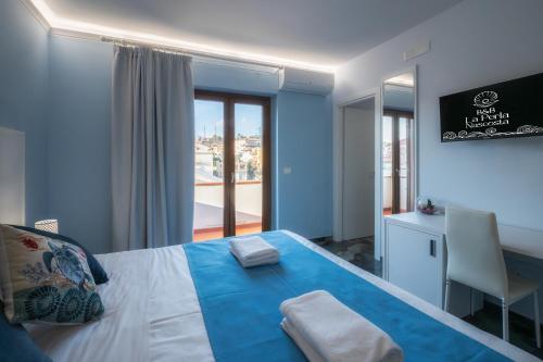 a blue bedroom with a bed with a desk and a window at La Perla Nascosta in Belvedere Marittimo