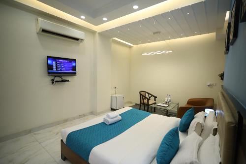 - une chambre avec un lit et une télévision murale dans l'établissement Asian Suites Cyber Park Gurgaon, à Gurgaon