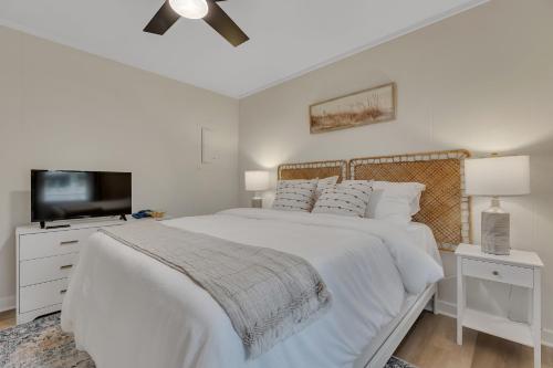 1 dormitorio blanco con 1 cama y TV de pantalla plana en Beachy 3BD Bungalow One Block from Scenic Walkway, en Oak Island