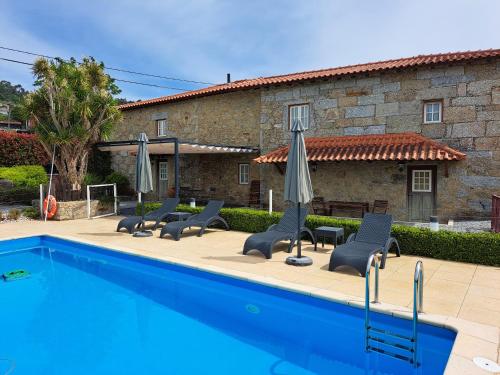 a pool with chairs and umbrellas next to a building at Casa Cachada in Braga