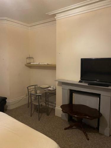 Habitación de hotel con TV, mesa y sillas en Palace, en Crystal Palace